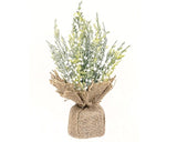 Faux plant in a burlap sack on a white background