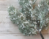 Decorative branch with green leaves and white berries on a wooden surface