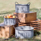 Set of three metal buckets on a wooden crate with apples outdoors