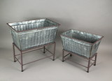 Two metal planters on stands against a gray background
