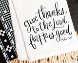 Textile with 'Give thanks to the Lord for He is good' quote on a white background