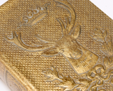  This small decorative book box is inspired by rustic cabin decor. It features a textured faux leather wrap displaying the exterior of a vintage book with an aged metallic gold finish on an embossed deer emblem design. It also displays a coordinating embossed gold design on its side to give the appearance of a book spine when on a shelf. 