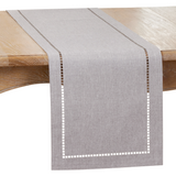 Gray table runner with white hem on a wooden table