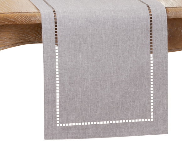 Gray table runner with white hemstitching on a wooden table