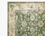 A close-up of a traditional oriental rug showing the corner, featuring a green floral field with an ornate cream and beige border.