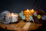 Candle holders with lit candles on a wooden surface against a dark background