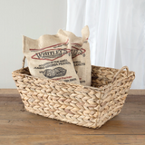 Two burlap bags with 'Whitley's Peanut Factory' branding in a woven basket on a wooden surface.