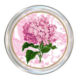 A round decorative item featuring an illustration of a pink hydrangea with green leaves over a pink toile pattern background, surrounded by a silver-toned metallic rim.