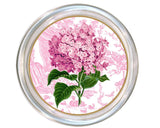 Round decorative glass coaster featuring a pink hydrangea flower with green leaves over a pink toile-style pattern, surrounded by a silver-toned rim.