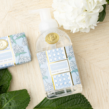 Hand soap dispenser with floral design on a wooden surface with flowers and leaves.