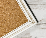 Cork bulletin board with white frame on wooden surface