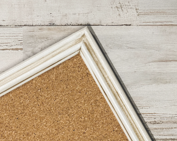 Complete your mud room command center with this hand-painted cork board that complements almost any style decor.

The wooden vintage frame of this message board is painted in soft white. It is then antiqued using a java brown glaze. After curing, the frame is sealed with wax for durability. The original glass has been replaced with a foam core board that has cork permanently adhered to it. It is all secured with new mounting hardware. Hanging hardware is also attached for horizontal or vertical display.
