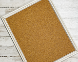 Cork bulletin board with a white frame on a wooden surface