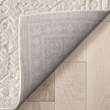 ivory textured rug on a beige carpet and wooden floor