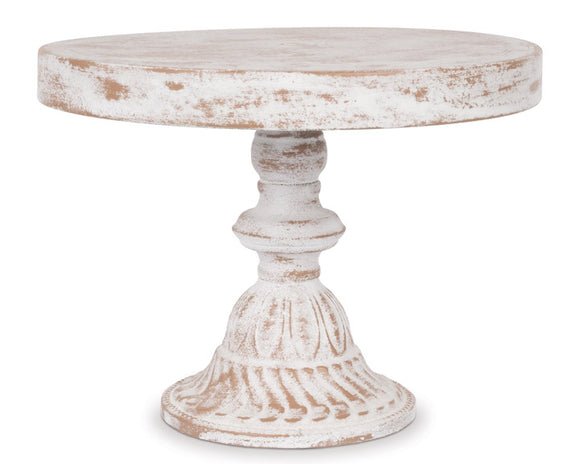 Round wooden cake stand with a white distressed finish on a white background