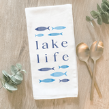 Blue 'Lake Life' kitchen towel  Form and function come together in this fun, flour-sack tea towel. Featuring a hand-drawn design, each towel has the phrase, "Lake Life," in dark blue letters. The phrase is surrounded by fish in light blue and dark blue shades. This would be a perfect gift for a lake enthusiast.&nbsp;  This item is proudly made in the USA.  Materials: Cotton  Dimensions: 27" wide x 27" long  Care: This item is machine washable.