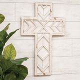 Decorative wooden cross with geometric patterns on a light wooden wall.