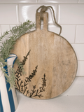 Wooden cutting board with floral design on a tiled wall