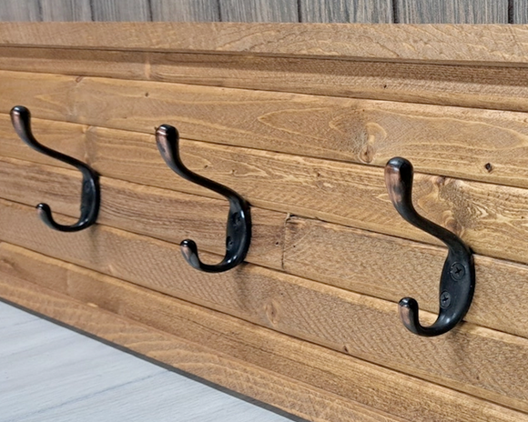 Rustic American-made light pine coat rack
*Made to order*

This rustic wood coat rack is great for hanging many items including coats, hats, towels aprons and many more. The coat racks are made using a solid pine board that is then covered and framed with rough-sawn wooden slats. Metal coat hooks are secured through both layers of wood with screws. Each coat rack is handmade using natural wood so every item will be unique. The wood may have knots, cracks, nail holes and natural wear in the finish. 
