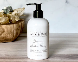 Milk & Pail lotion bottle on a wooden surface with decorative elements.