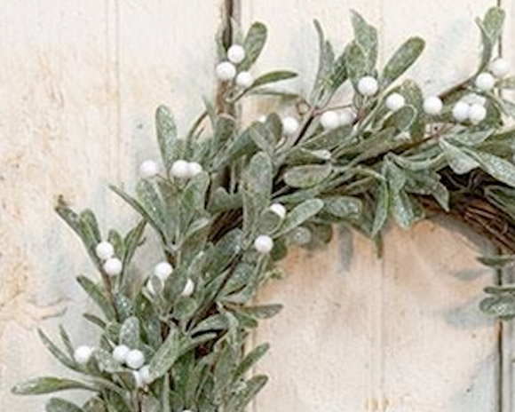 Decorative wreath with green leaves and white berries on a wooden background