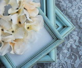 robin's egg blue hand-painted wooden vintage picture frame set atop a lace background