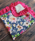 Floral-patterned blanket with pink ruffle on a wooden surface