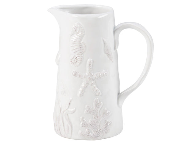 White ceramic pitcher with floral embossing on a white background