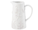 White ceramic pitcher with floral embossing on a white background