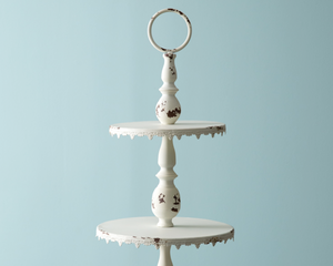 Ornate distressed creamy white tiered tray

Display desserts for a wedding or small items for your store on this feminine display stand. It features a loop to carry and is a large piece measuring almost 3 feet tall. It is made of metal and not food safe. It is recommended to use with dollies or liners.

Materials:
Metal

Dimensions:
14" diameter x 33" high