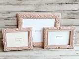 Three decorative pink frames on a wooden surface