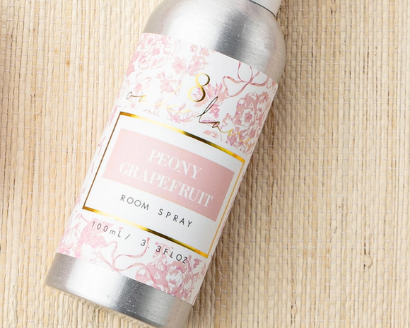 Peony Grapefruit room spray bottle with floral label on a woven surface