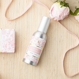Bottle of 'Floral Bloom' spray with floral decorations on a wooden surface