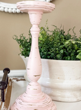 Pink candle holder with green plants in the background