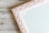 Decorative pink frame with intricate patterns on a light wooden surface