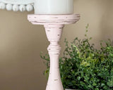 Pink candle holder with a white candle on a beige background
