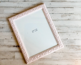 Pink ornate picture frame on a wooden surface