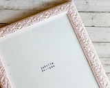 Decorative pink frame with 'Jabella Design' branding on a wooden surface