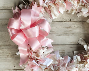 Pink and beige ribbon wreath on a wooden surface