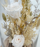 Bouquet of white and beige flowers in a clear vase on a light background