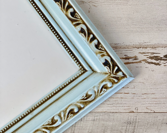 Decorative mirror frame with intricate gold designs on a wooden surface