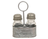 Galvanized metal salt &amp; shaker set caddy

This caddy is a vintage-inspired piece made of galvanized silver metal with a raised pattern and a circular handle attached to the middle. Either side of the caddy holds a glass seasoning shaker with a screw-top metal lid with holes at the top. Fill these shakers with salt and pepper, and display this caddy on any tabletop, riser, or other kitchen surface for easy access with a decorative, farmhouse-inspired touch.

Materials:
Metal, glass

Dimensions:
4 1/4" wi