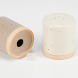 Neutral beige speckled salt &amp; pepper shaker set

This set of stoneware salt and pepper shakers feature a cottage greige and cream finish on each with bare ceramic accents. The shakers include unique openings to tell them apart, as well as plastic stoppers for easy refilling and cleaning. This rustic set of tabletop accessories are perfect for everyday gatherings.

Materials:
Stoneware, ceramic, rubber

Dimensions:
2 3/4" diameter x 3" high