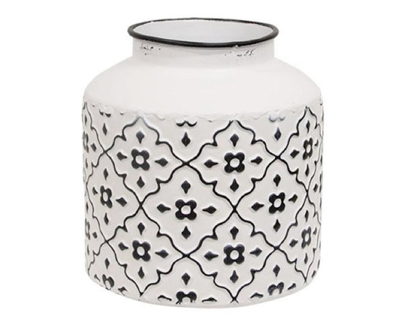 This short vase is a decorative container made of metal with a distressed white finish. It has a black rim and features a raised black floral pattern, offering a chic, yet vintage touch. This vase is ideal for year-round or seasonal use, displayed filled with florals, greenery, and decorative picks and sprays. 