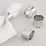 Silver napkin rings on a white surface with a white napkin.