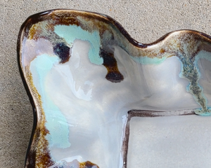 Ceramic dish with a unique glaze pattern on a textured surface