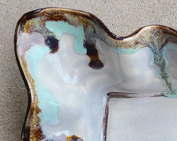 Ceramic dish with a unique glaze pattern on a textured surface