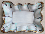 Decorative stoneware baking dish with wavy edge and turquoise and brown glaze on a beige background
