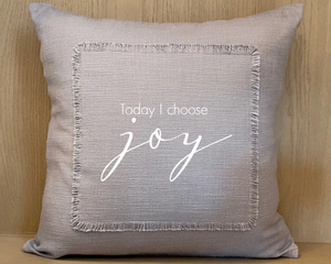 Gray pillow with 'Today I choose joy' text on a wooden background