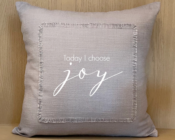 Gray pillow with 'Today I choose joy' text on a wooden background